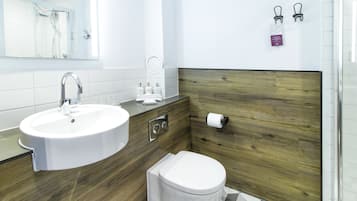 A modern bathroom with a white sink, wooden vanity, and a toilet.