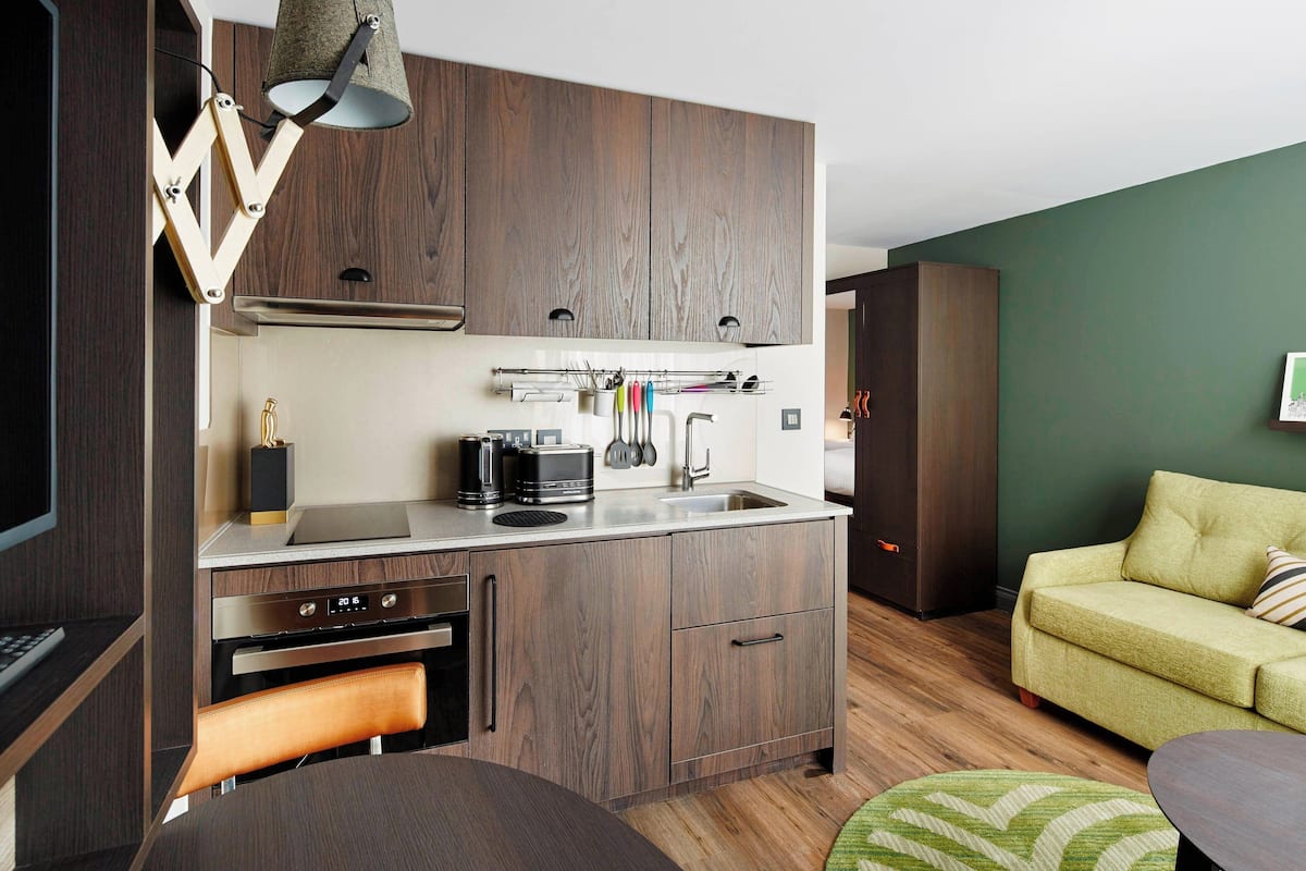 A compact kitchen with wooden cabinets, a built-in oven, and a coffee maker.