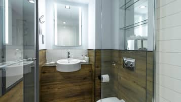 A modern bathroom with a glass shower enclosure, a wooden vanity, and a white sink.