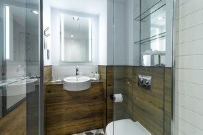A modern bathroom with a glass shower enclosure, a wooden vanity, and a white sink. - Residence Inn by Marriott London Kensington (London)