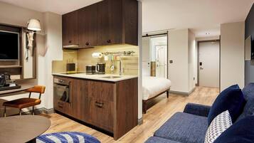 A compact living space with a kitchenette, a dining area, a sofa, and a bed.