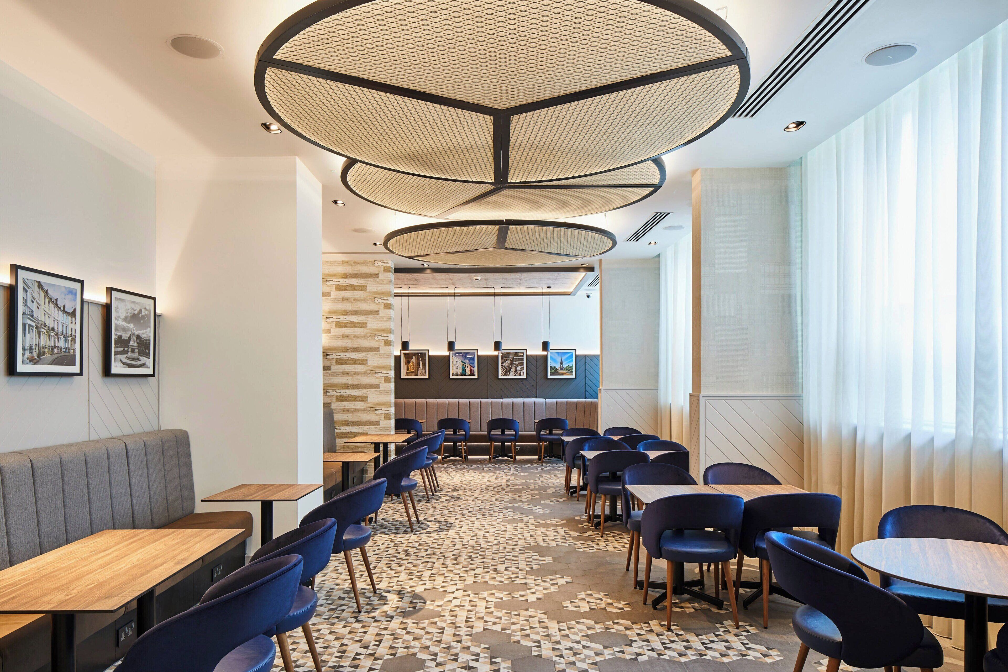 A modern restaurant interior with a central seating area, high ceilings, and a patterned floor.