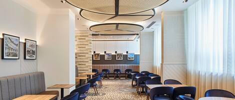 A modern restaurant interior with a central seating area, high ceilings, and a patterned floor.