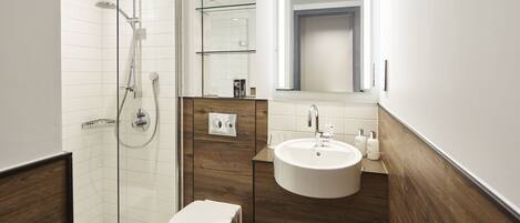 A modern bathroom with a glass-enclosed shower, a wooden vanity with a sink, and a toilet.