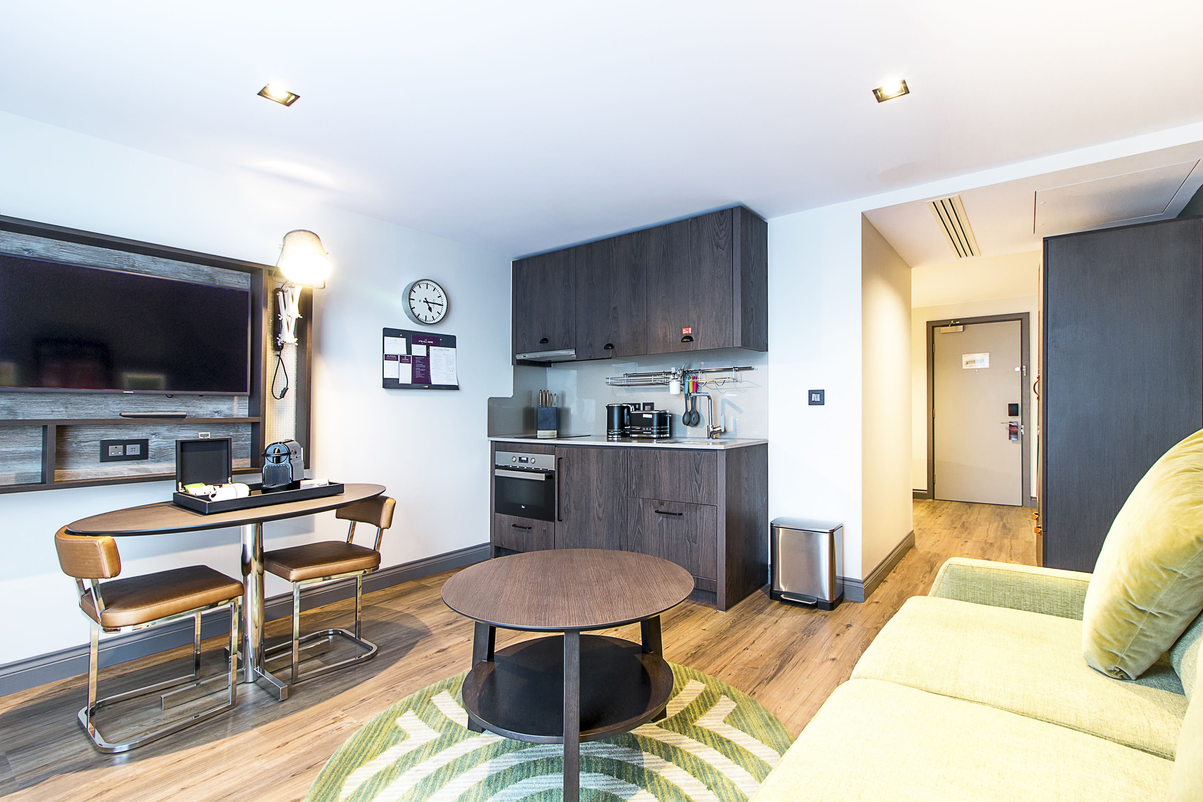 A compact living space with a kitchenette, a dining area with a round table, and a sofa.