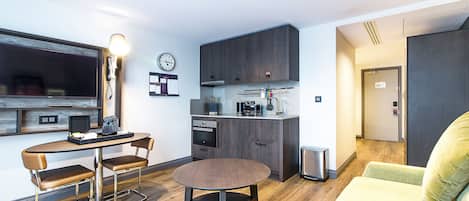 A compact living space with a kitchenette, a dining area with a round table, and a sofa.