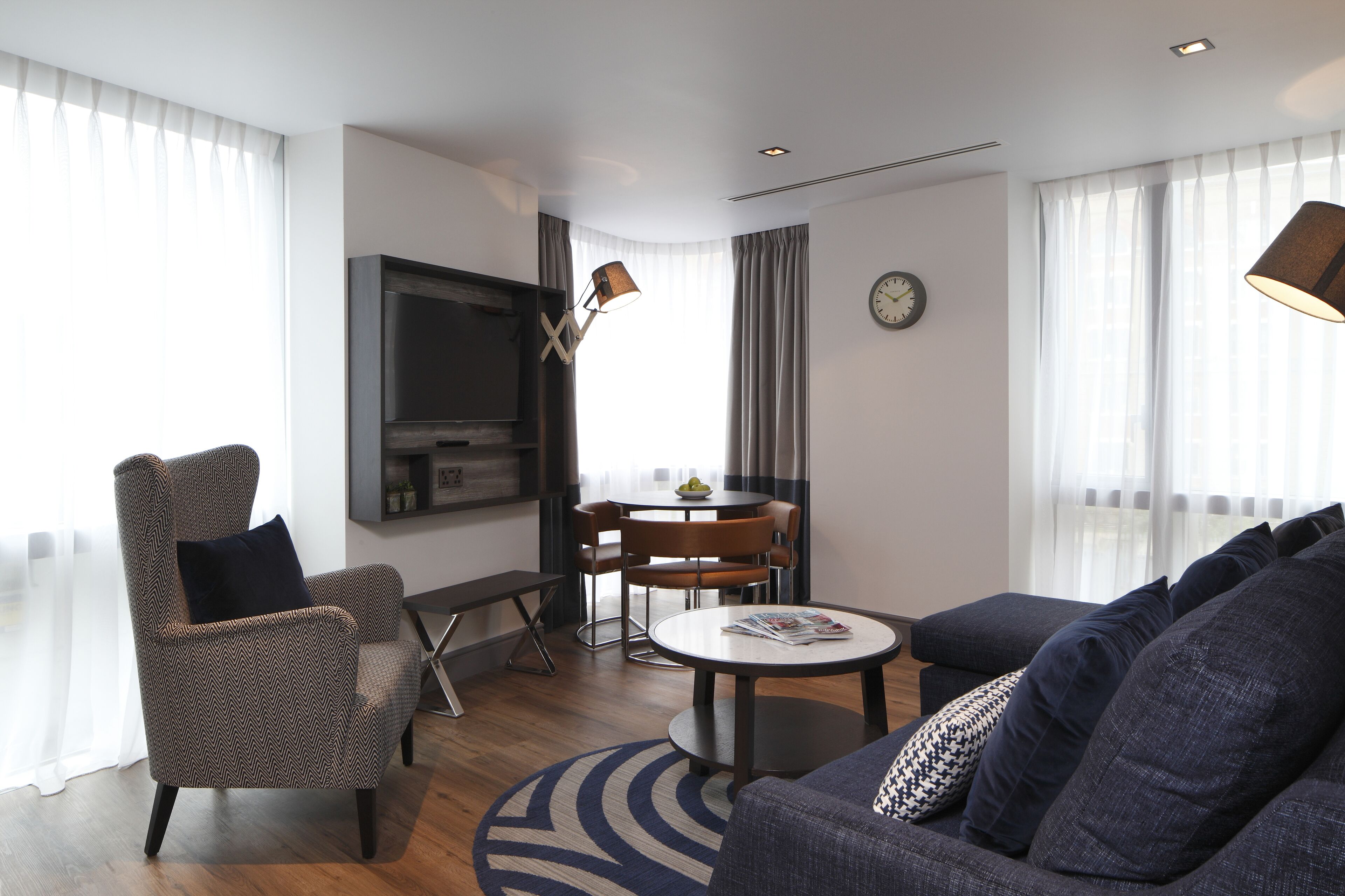 Un salon moderne comprenant un canapé, un fauteuil, une table à manger et un téléviseur.