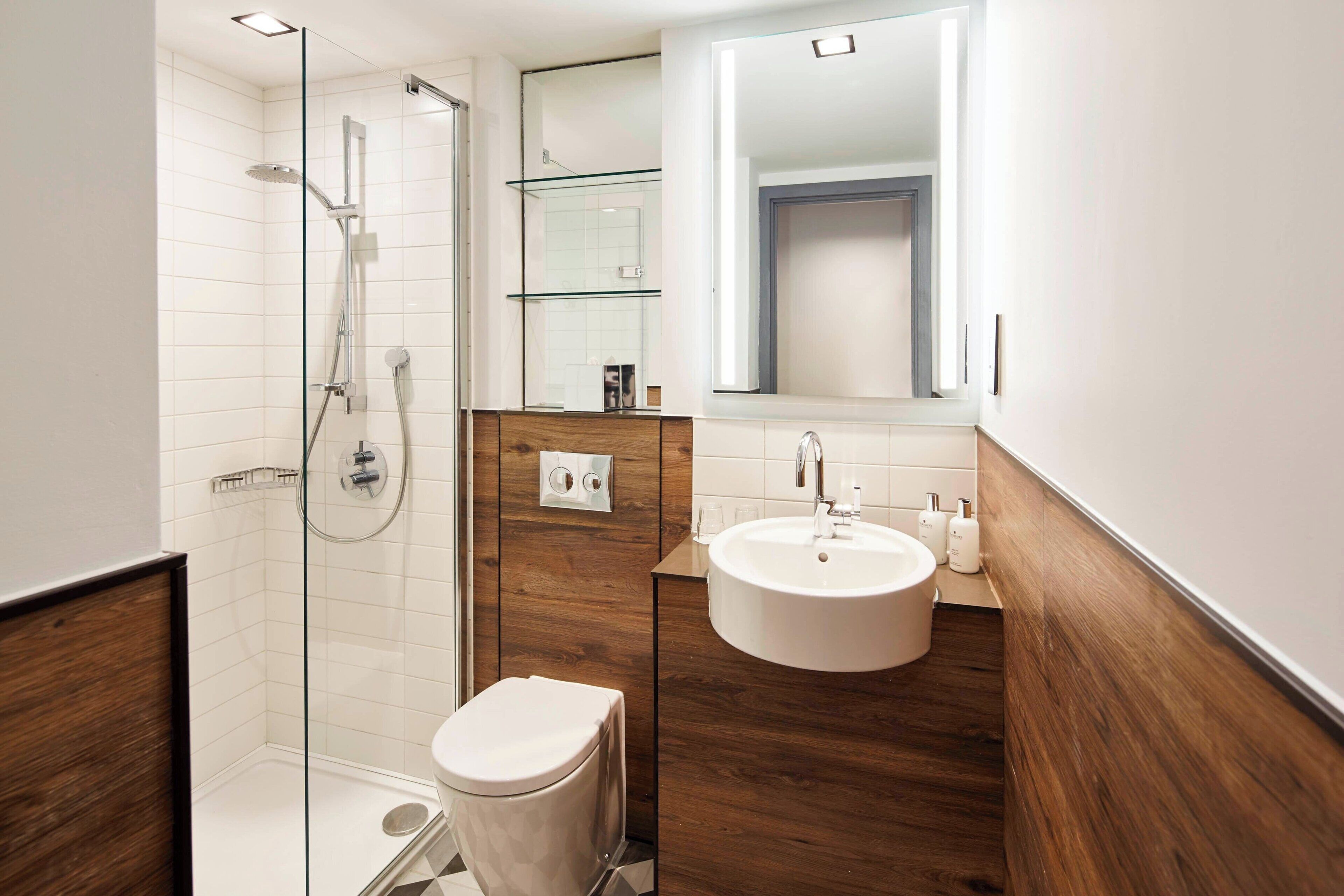 A modern bathroom with a glass-enclosed shower, a wooden vanity with a sink, and a toilet.