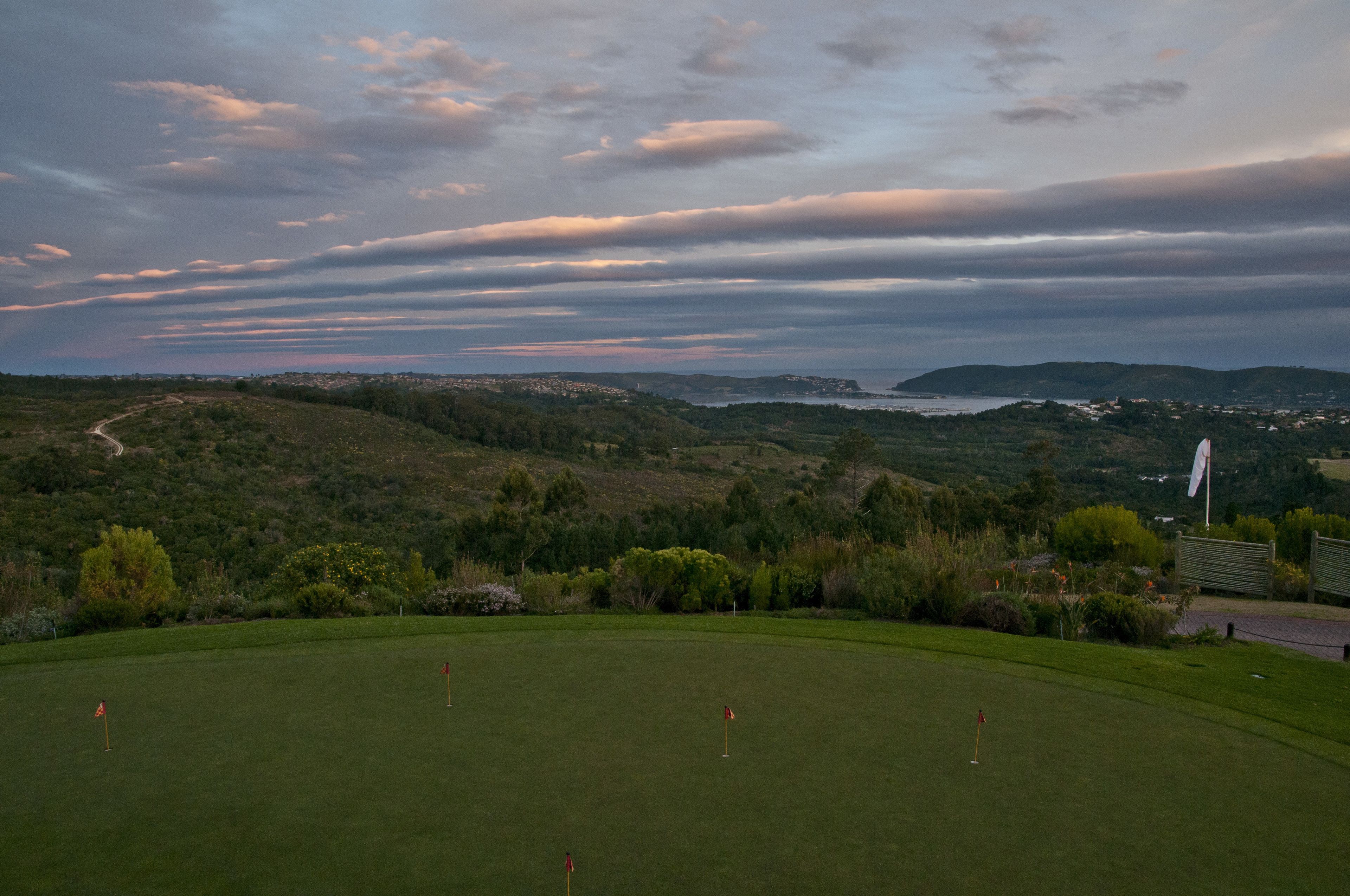A golf course with a scenic view of hills and a body of water in the distance.