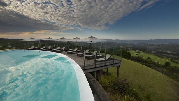 A swimming pool with lounge chairs and umbrellas overlooking a scenic landscape. - Simola Hotel, Country Club & Spa (Knysna)