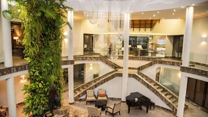 A multi-level atrium with a central staircase, seating areas, and a large indoor plant. - Simola Hotel, Country Club & Spa (Knysna)
