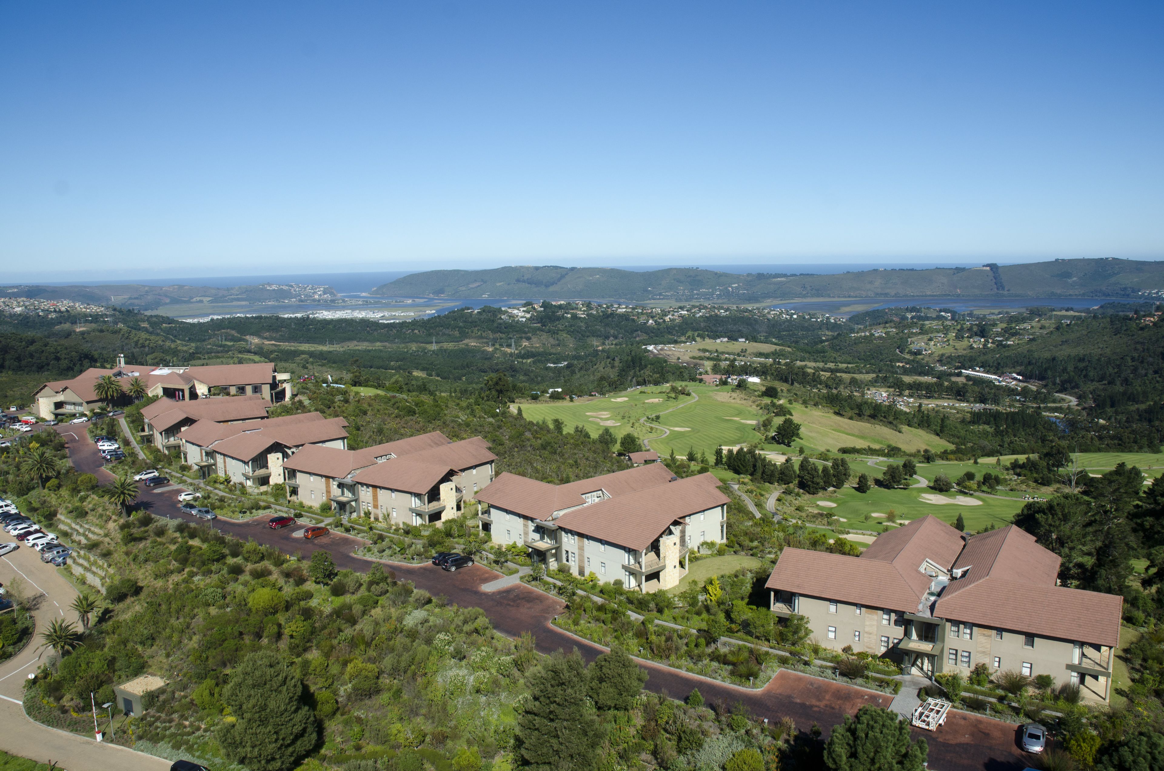 A residential area with multiple two-story houses, a golf course, and a clear view of distant hills.