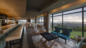 A modern hotel lobby with a bar, seating area, and large windows offering a scenic view. - Simola Hotel, Country Club & Spa (Knysna)