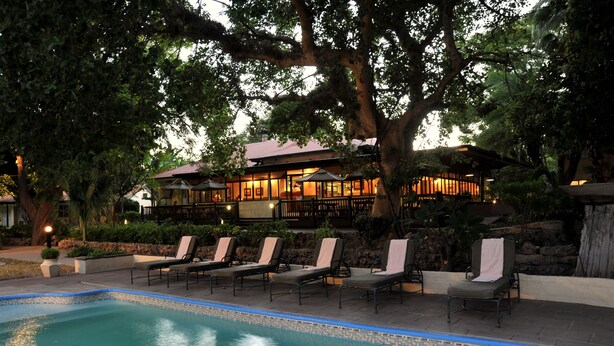 A pool area with lounge chairs and a building in the background.