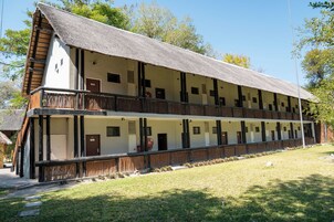 Un edificio de dos pisos con techo de paja, varias habitaciones y un balcón.