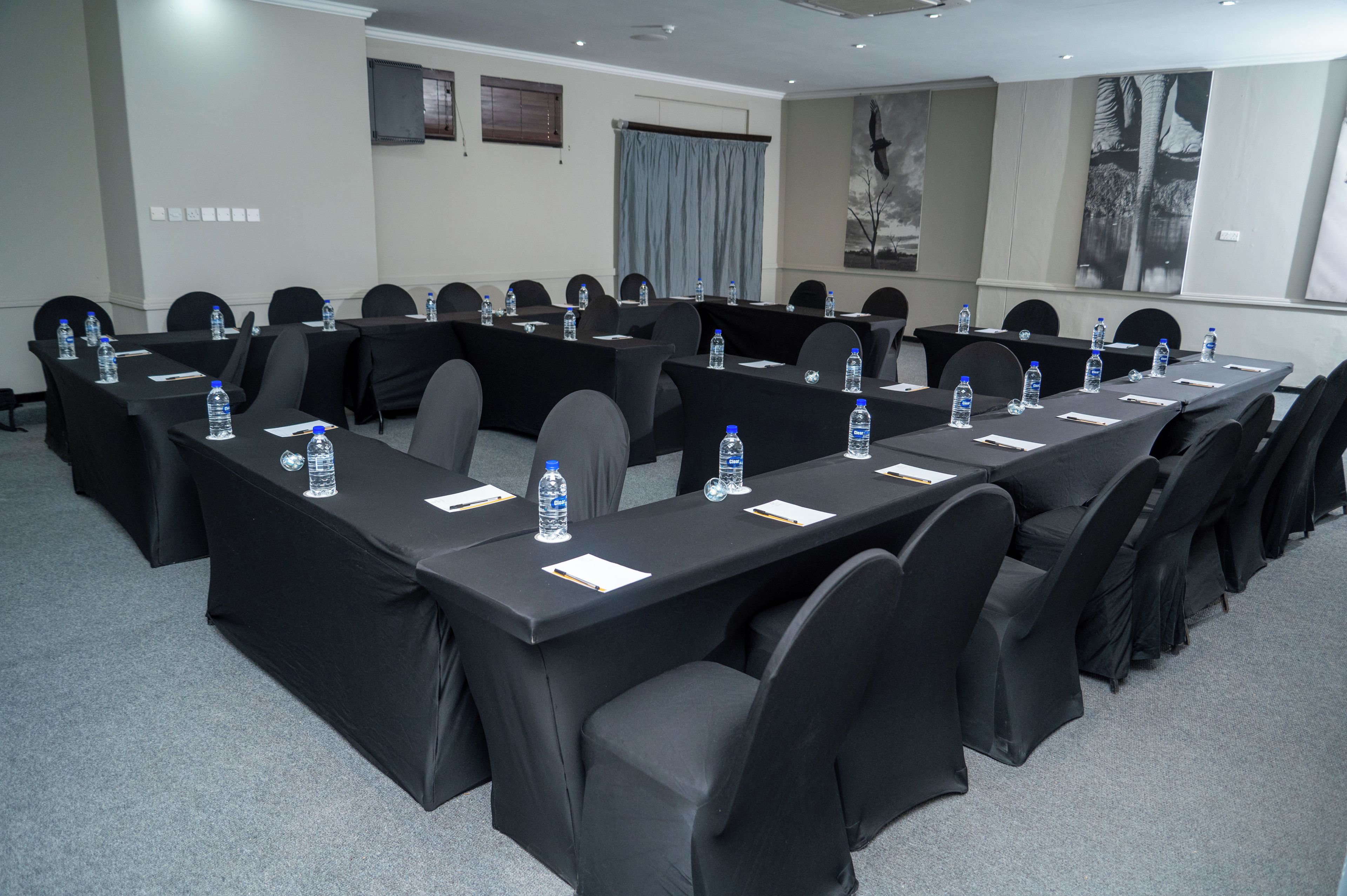 A conference room with multiple tables, chairs, and water bottles.