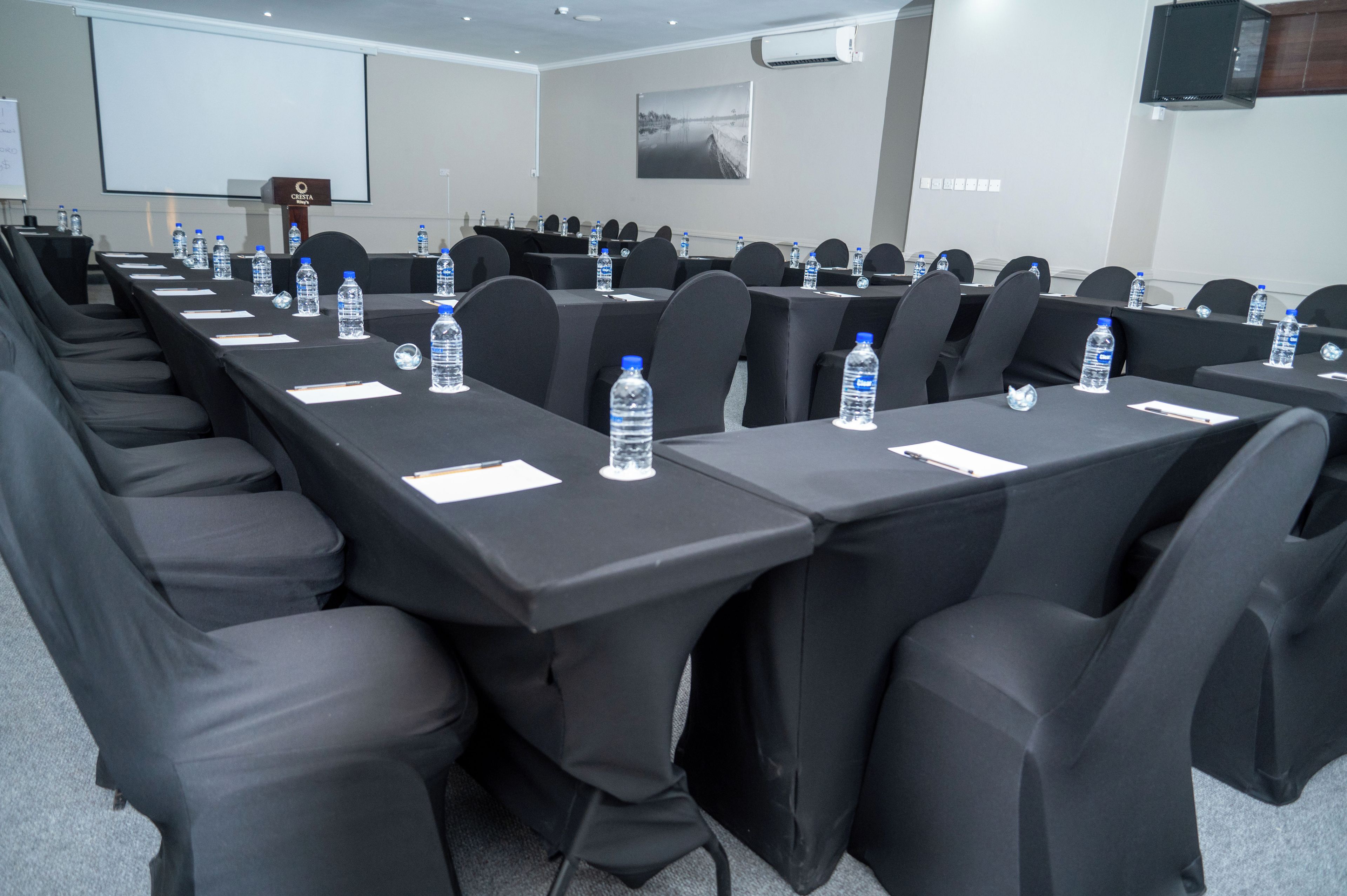 A conference room with rows of tables, chairs, and water bottles.