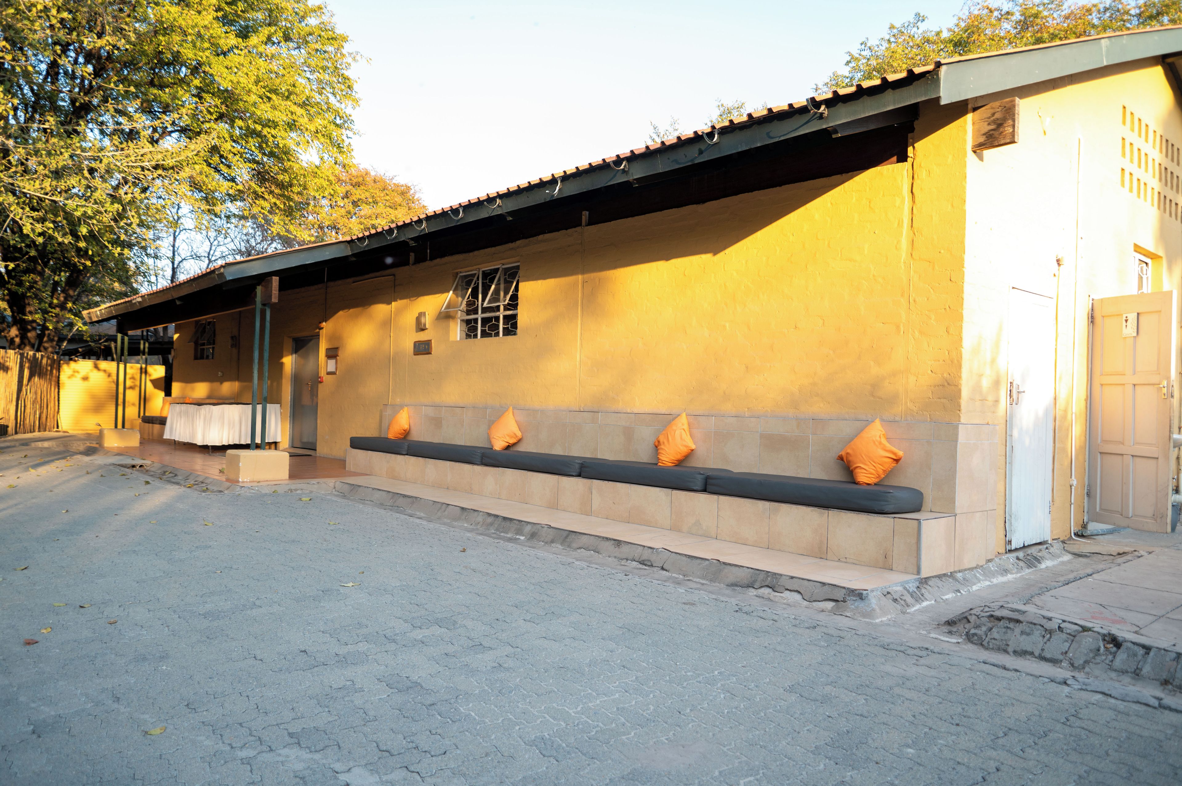 A building with a yellow exterior, a tiled bench area, and a door with a window.