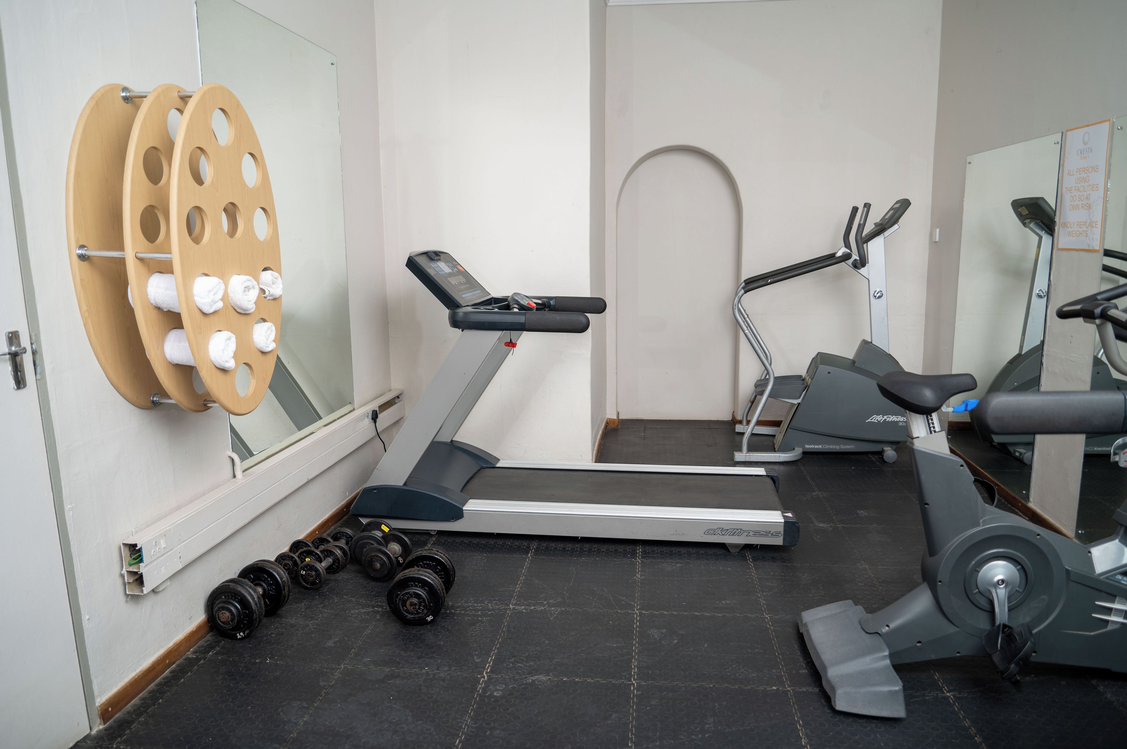 A gym with exercise equipment including a treadmill, elliptical, and weights.
