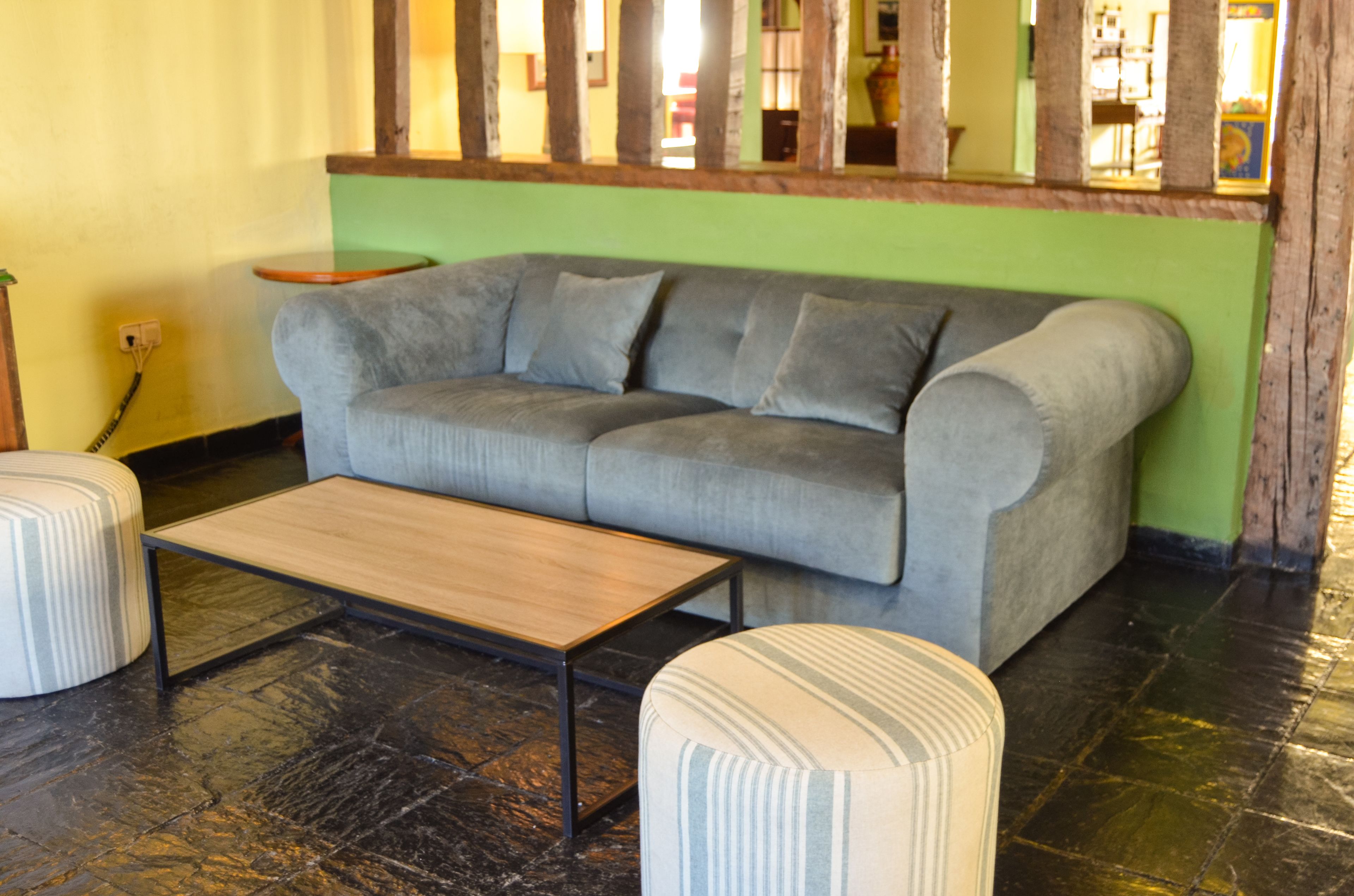 A living room with a grey sofa, a wooden coffee table, and striped ottomans.