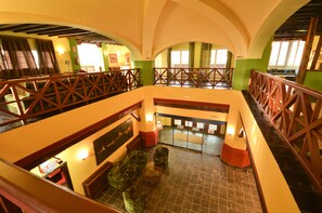 A multi-level hotel lobby with a central seating area, wooden railings, and a reception desk.