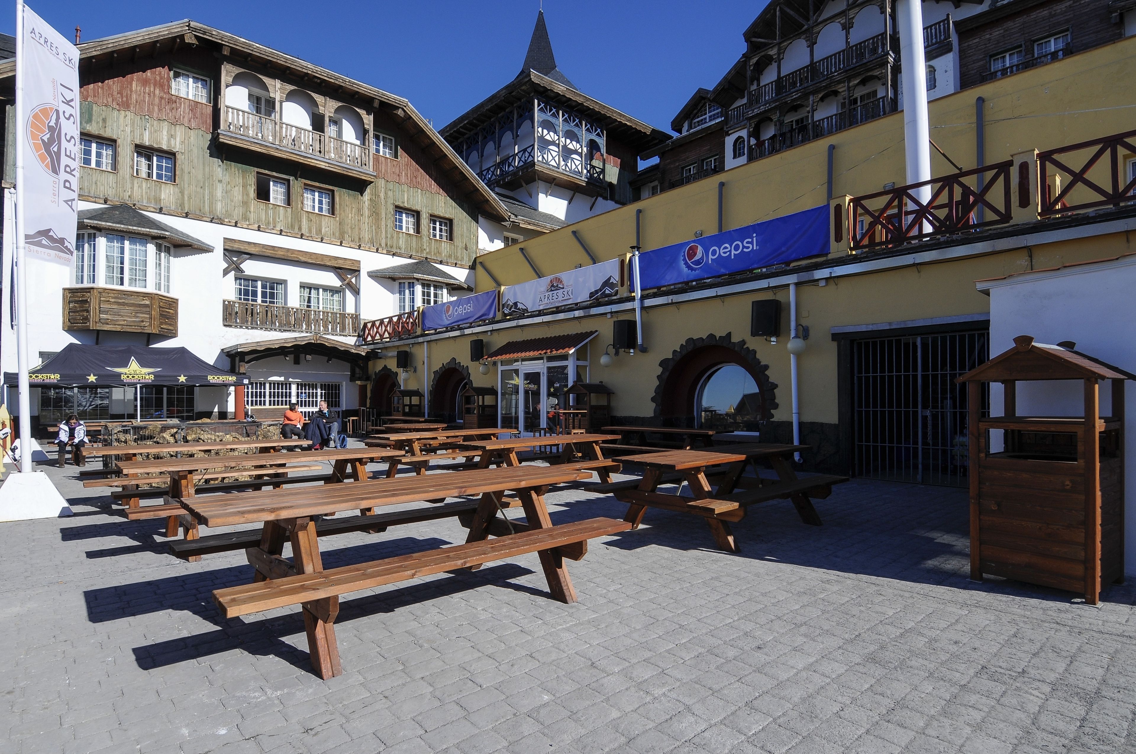 A traditional European-style building with wooden benches and a Pepsi banner.