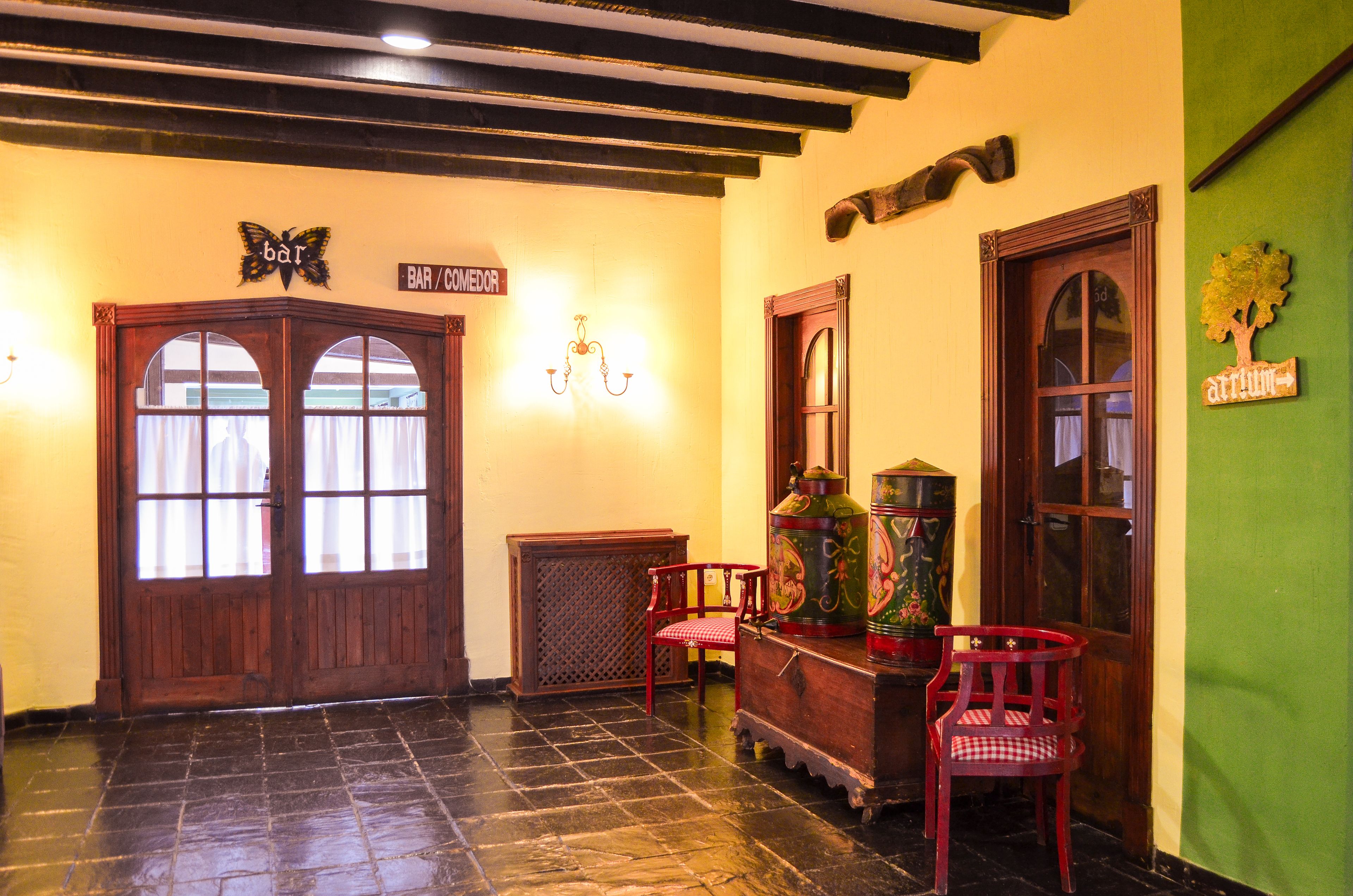 Un área de bar con puertas de madera, un candelabro y dos sillas rojas.