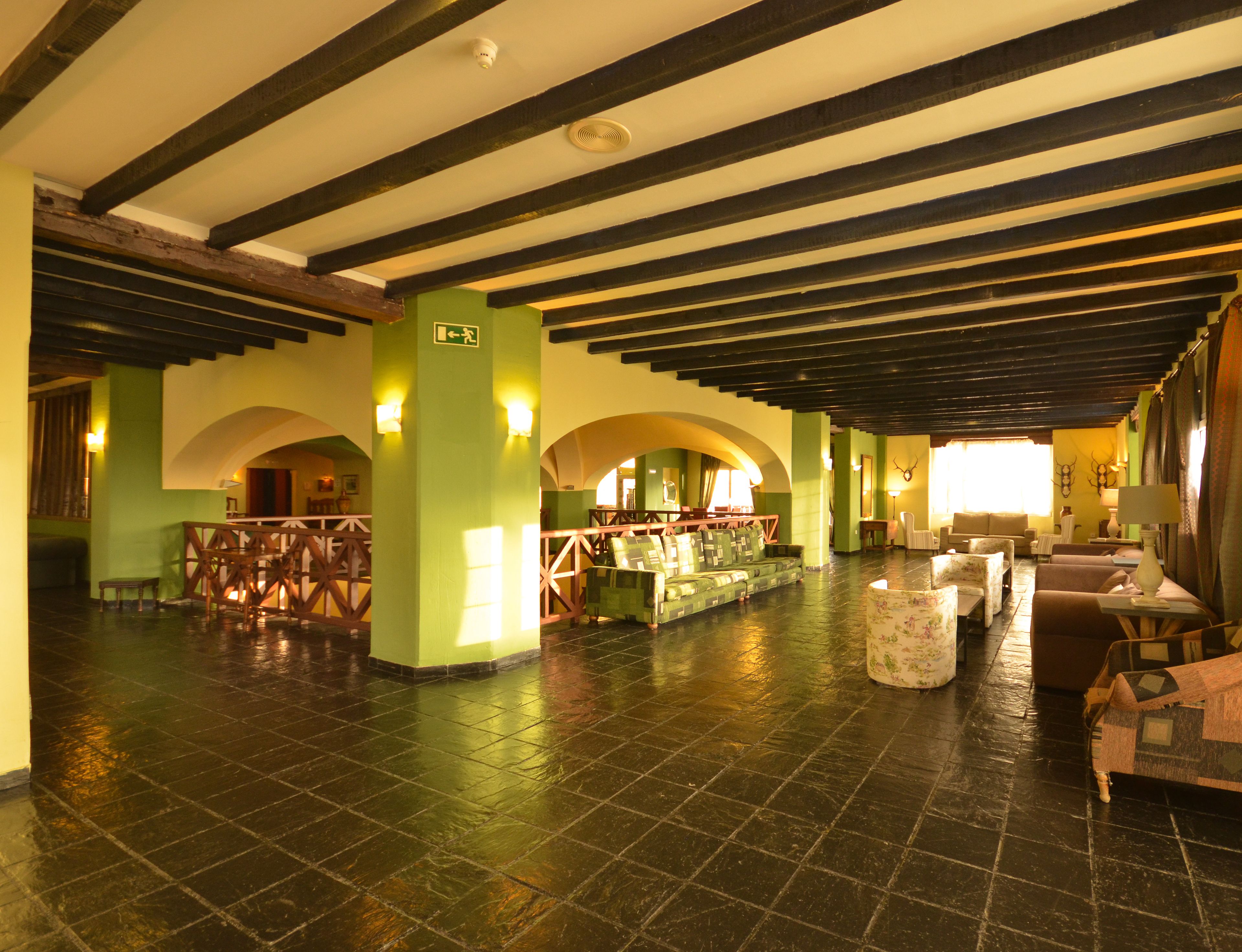 A spacious lobby with high ceilings, exposed beams, and a central seating area with sofas and tables.