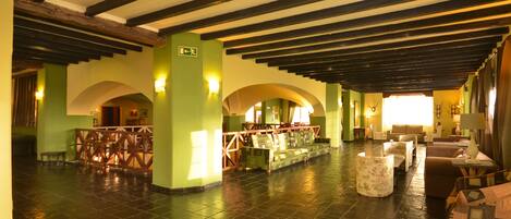 A spacious lobby with high ceilings, exposed beams, and a central seating area with sofas and tables.