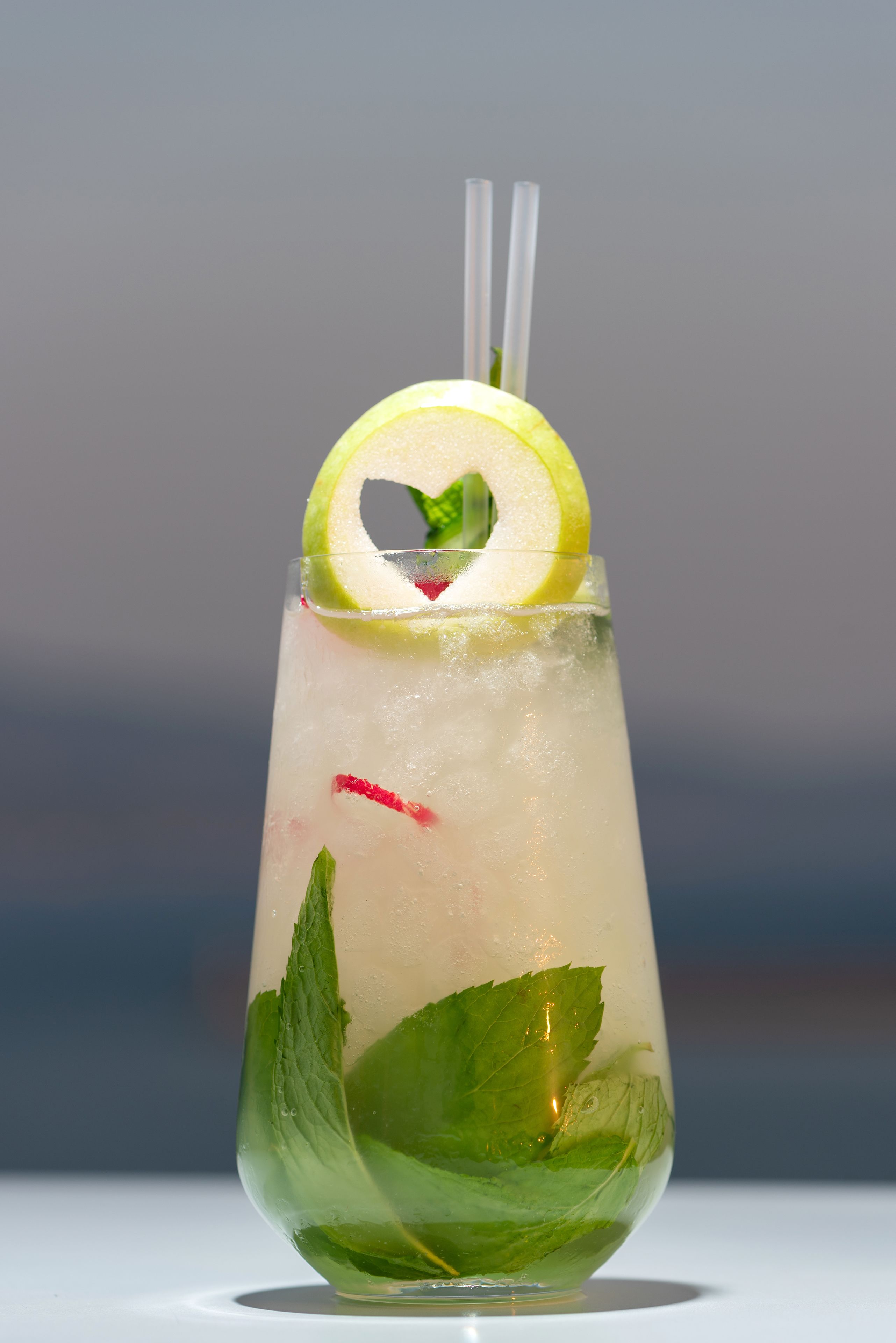 Un vaso transparente con una rodaja de lima y hojas de menta.