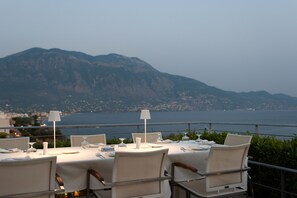 A table set for dining with a view of a mountainous landscape and the sea in the background. - Pharae Palace Hotel (Kalamata)