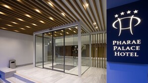 A modern hotel lobby with glass doors, a wooden ceiling, and a sign for the Pharae Palace Hotel. - Pharae Palace Hotel (Kalamata)