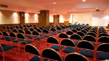 A conference room with rows of chairs, a podium, and a projection screen.
