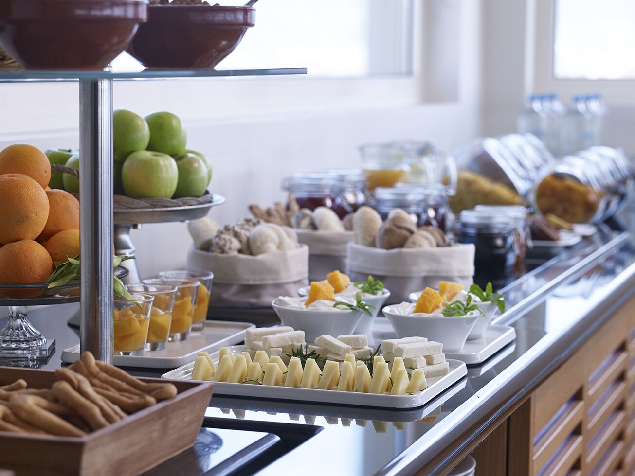A buffet with various food items including fruits, cheeses, and pastries.