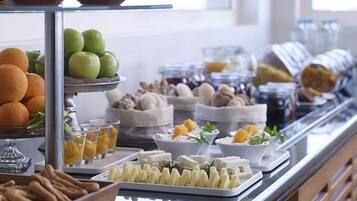 Un buffet proposant une variété de plats, notamment des fruits, des fromages et des pâtisseries.