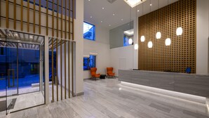 A modern lobby with a reception desk, two orange chairs, and a large wooden wall with circular lights. - Pharae Palace Hotel (Kalamata)
