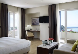 Una habitación de hotel con una cama, un escritorio con una computadora portátil, un televisor y un balcón con vistas.