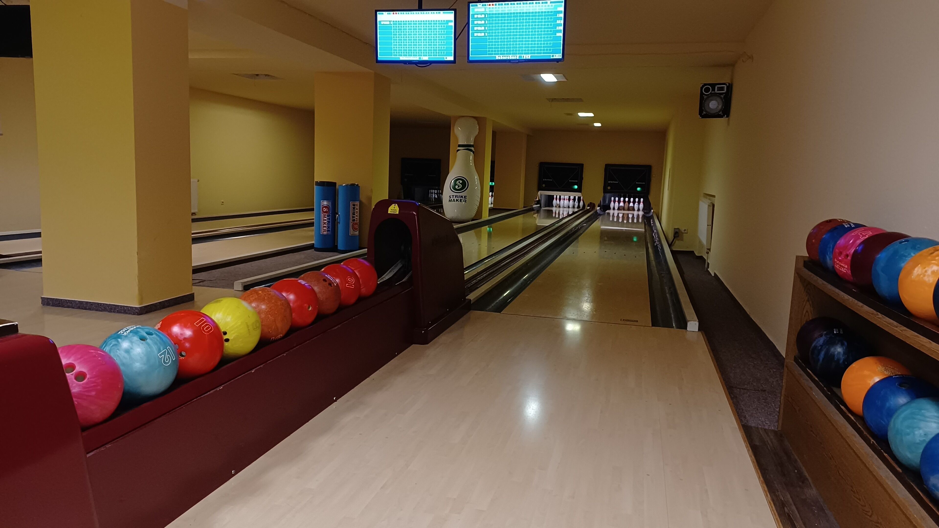 A bowling alley with lanes, bowling balls, and a bowling machine.