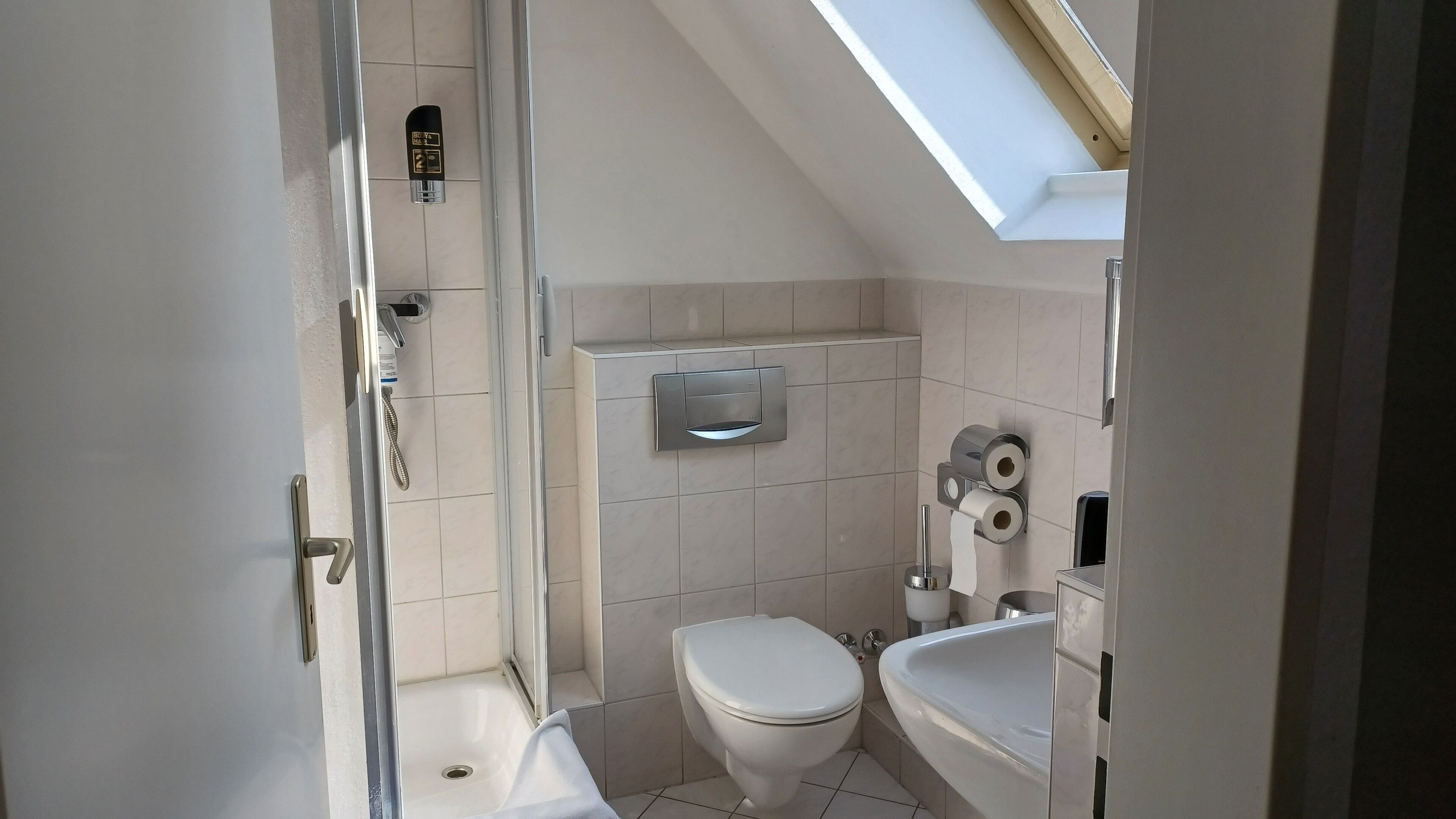 Une petite salle de bain moderne, équipée d’une douche, de toilettes et d’un lavabo.
