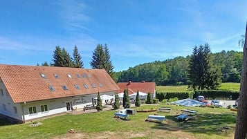 Een gebouw met twee verdiepingen, voorzien van een rode dakbedekking, omgeven door grasvelden en bomen.