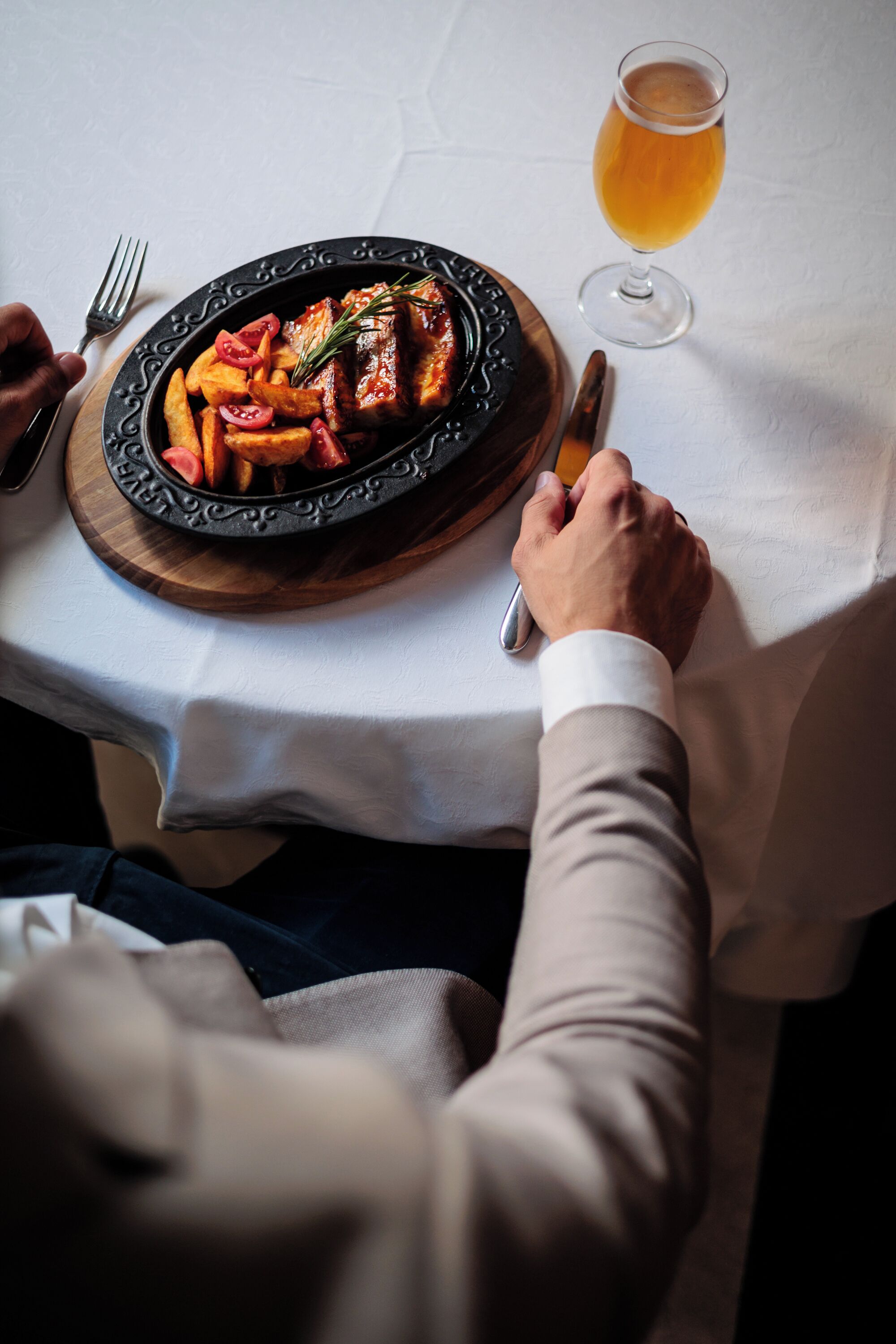 Una mesa de comedor con un plato de comida, una jarra de cerveza y cubiertos.