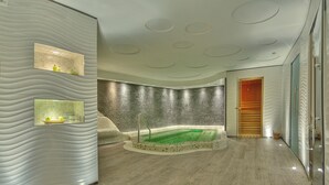 Ein Spa-Raum mit einer großen Badewanne, strukturierter Wandgestaltung und einer Holztür.