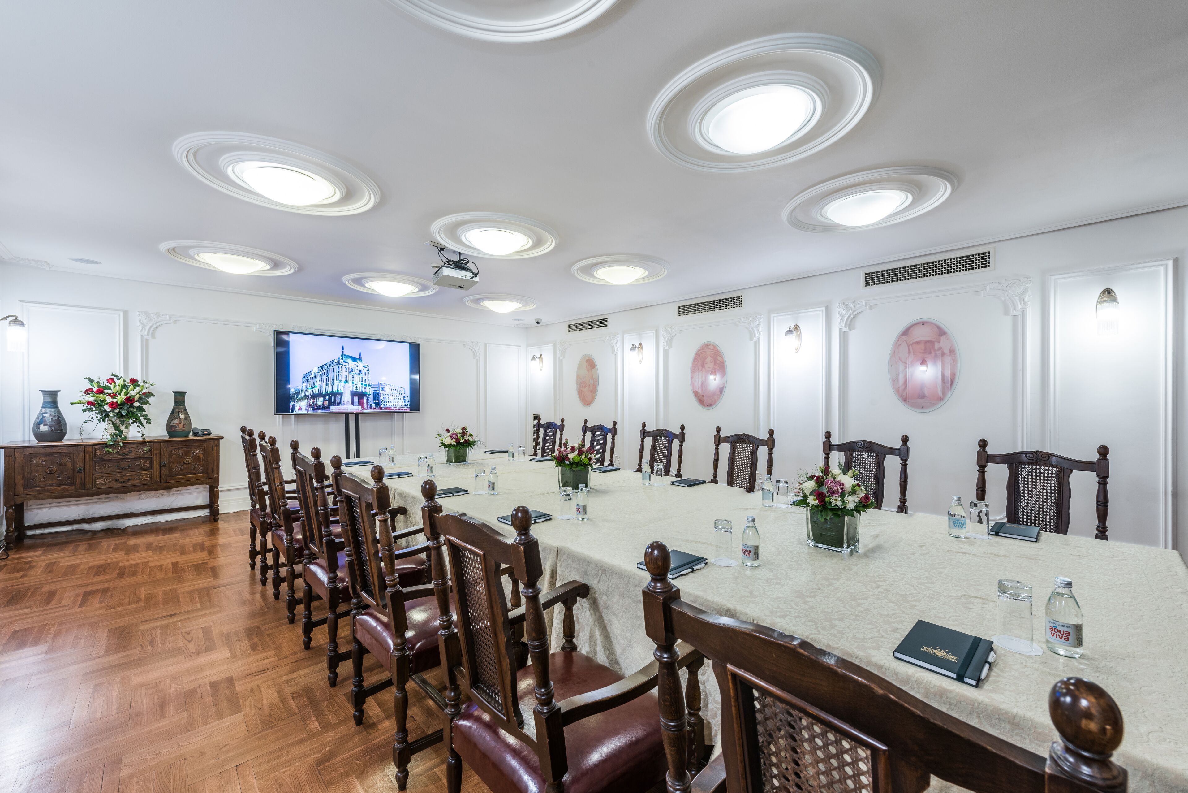 A conference room with a long table, wooden chairs, a television, and decorative wall panels.