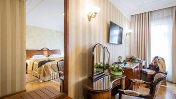 Una habitación de hotel con cama, escritorio con silla, televisión y espejo.