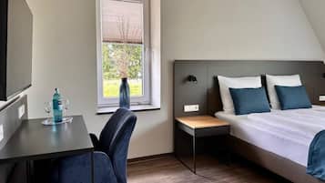 A bedroom with a bed, bedside table, and a desk with a chair.