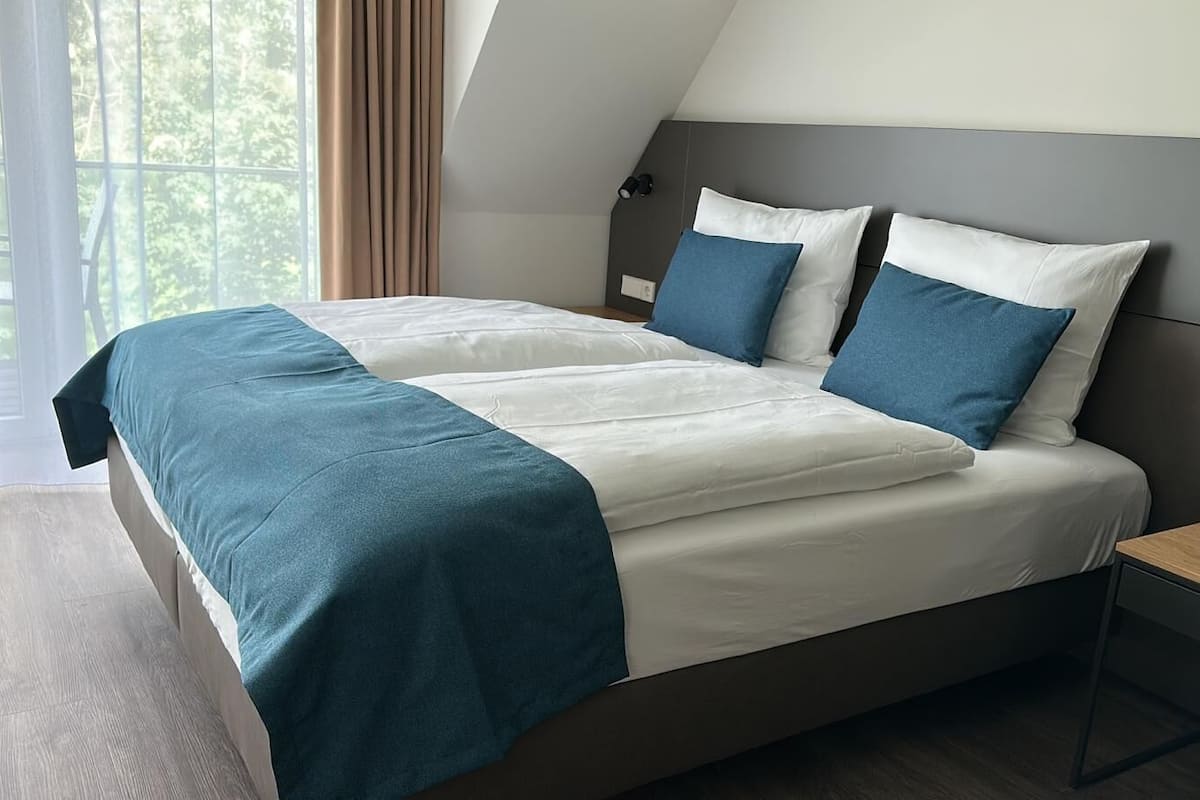 A modern bedroom with a bed, a bedside table, and a window with curtains.