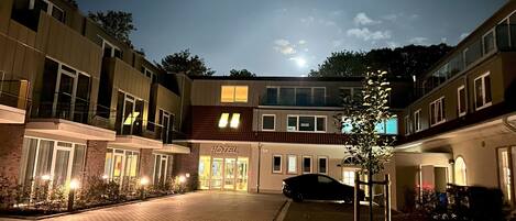 Ett hotell med en fasad av tegel, en bil parkerad framför och en klar stjärnhimmel.