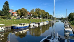 A canal with boats docked on both sides, surrounded by greenery and buildings. - Hotel Schöne Aussicht, Stilvoll modern, direkt am Rüstersieler Hafen (Wilhelmshaven)