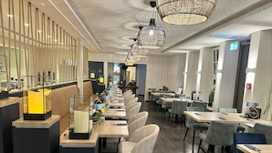 A modern restaurant with long communal tables, individual booths, and a bar area. - Hotel Schöne Aussicht, Stilvoll modern, direkt am Rüstersieler Hafen (Wilhelmshaven)
