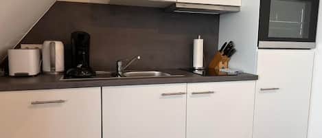 Een moderne keuken met witte kasten, een roestvrijstalen oven, een koffiezetapparaat en een messenblok.
